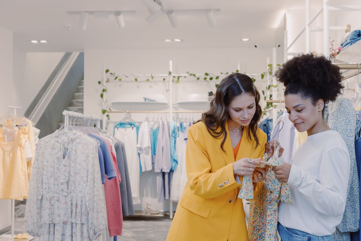 Two women browsing clothes in a stylish, modern boutique.